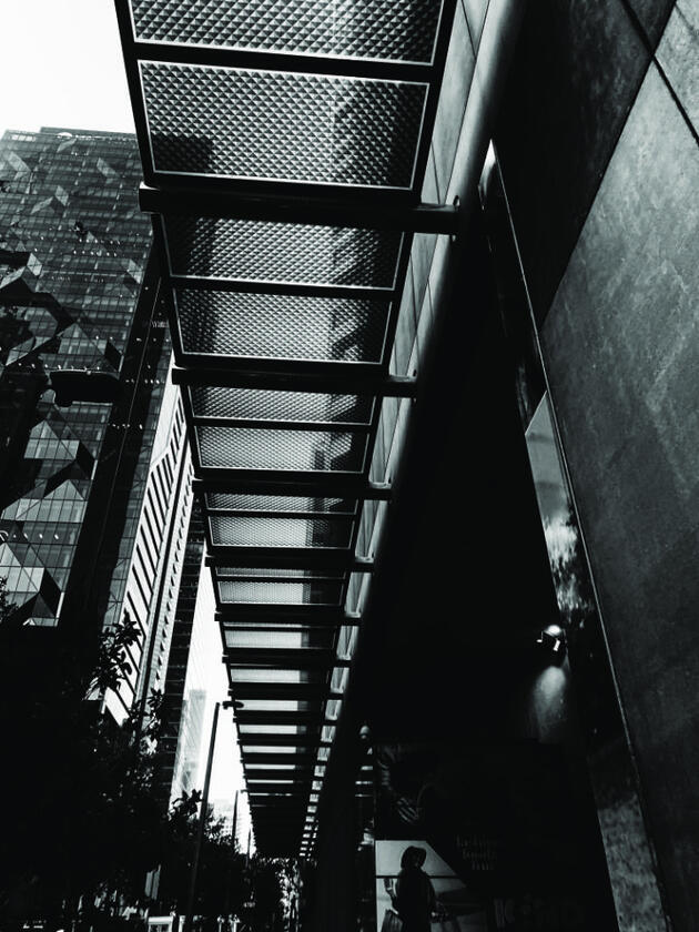 Perspective photo of a walkway under a building, glitched with vertical compression lines.