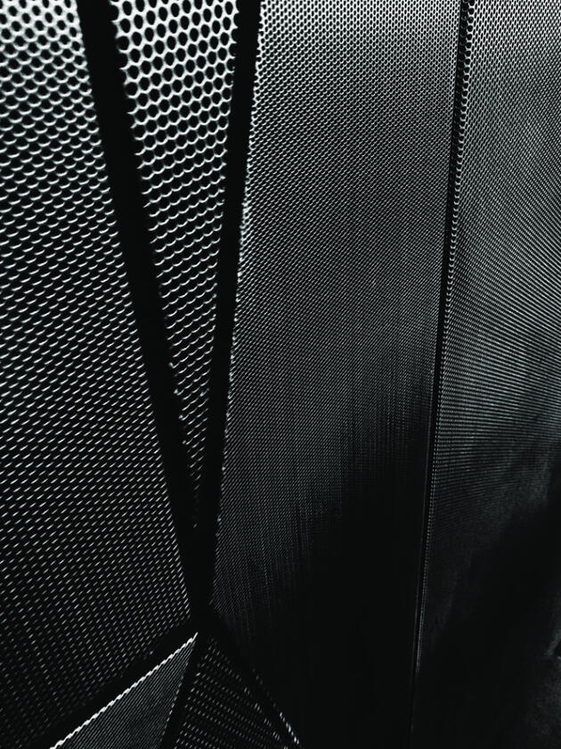 Minimal glitch photo with perforated metal panels in grayscale and subtle digital distortion.